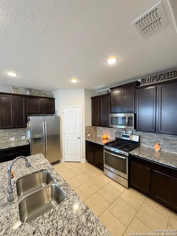 a kitchen with granite countertop a sink and a refrigerator