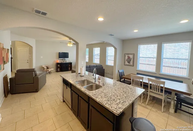 a kitchen with stainless steel appliances granite countertop a stove a refrigerator a sink a dining table and chairs