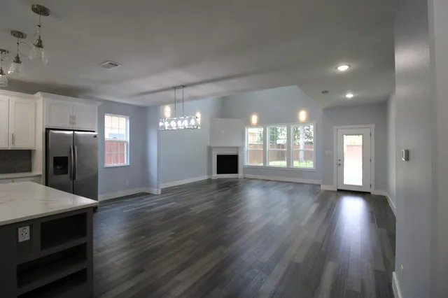 a view of an empty room with window and wooden floor