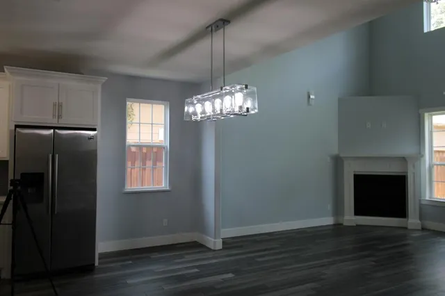 a view of an empty room with wooden floor fireplace and a window