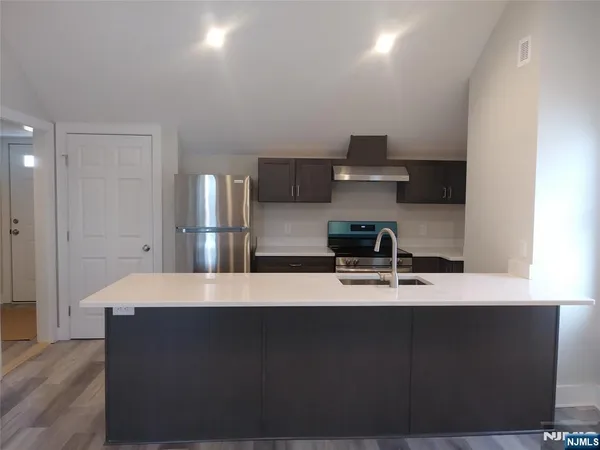 a living room with stainless steel appliances kitchen island sink refrigerator and stove