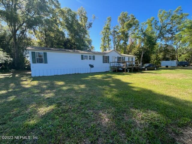a view of a house with a big yard and large trees