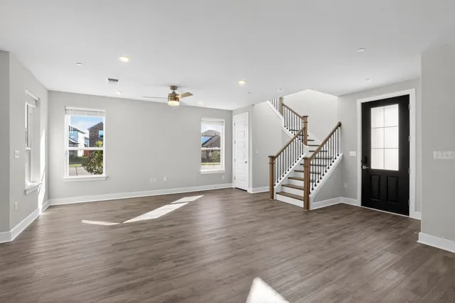 a view of an empty room with wooden floor stairs and a window