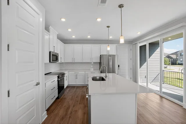 a kitchen with kitchen island a counter top space a sink stainless steel appliances and cabinets