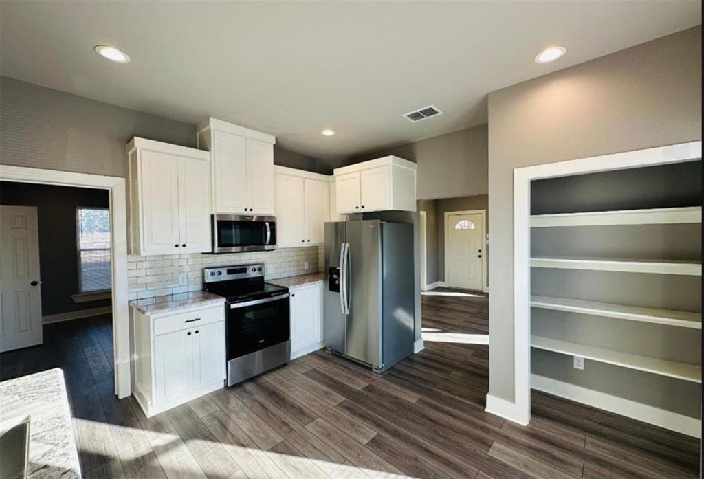 1408 East Houston Street Tyler, TX 75702 - Photo 6 of 15 a kitchen with stainless steel appliances kitchen island granite countertop a refrigerator and a stove top oven