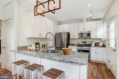 a kitchen with stainless steel appliances granite countertop a sink a stove a refrigerator cabinets and living room view