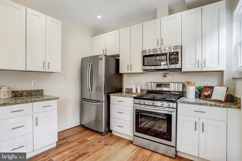 a kitchen with granite countertop white cabinets and stainless steel appliances