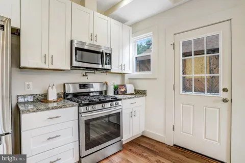 a kitchen with stainless steel appliances granite countertop white cabinets granite counter tops and a wooden floors