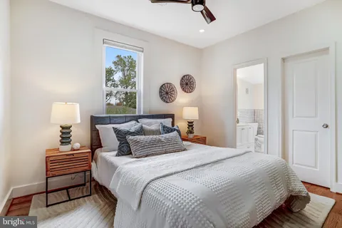 a bedroom with a bed and a lamp on table with wooden floor