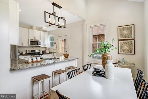 a kitchen with stainless steel appliances a table and chairs in it