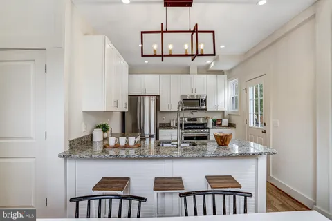 a kitchen with stainless steel appliances granite countertop a kitchen island a stove cabinets a refrigerator and a sink