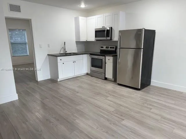 a kitchen with stainless steel appliances a refrigerator sink and microwave