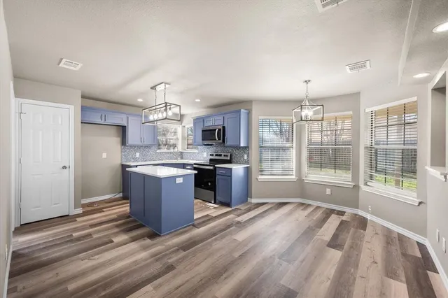 a large kitchen with a large counter top stainless steel appliances and cabinets