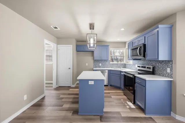 a large kitchen with a stove top oven a sink dishwasher a refrigerator and a microwave oven with wooden floor