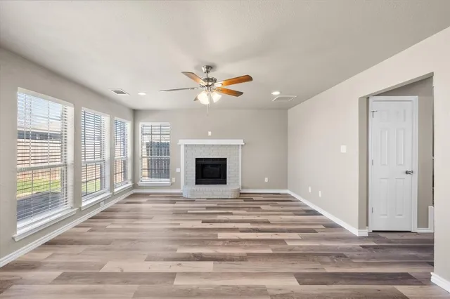 a view of an empty room with chandelier fan and wooden floor