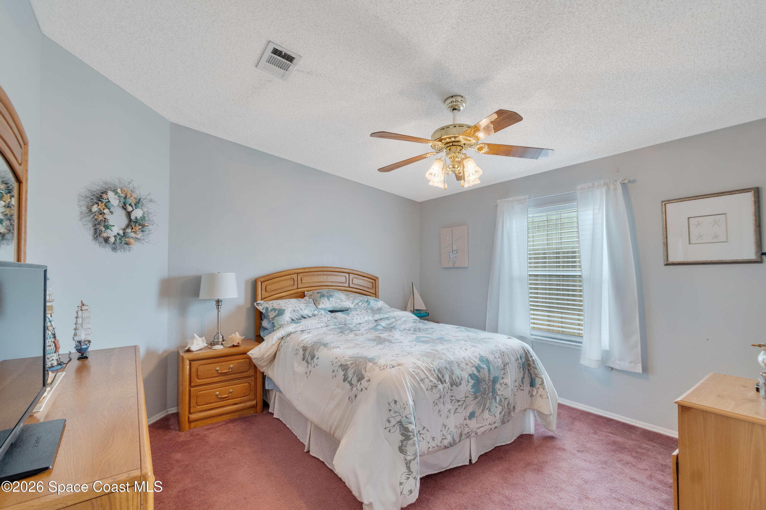 7669 Chasta Road Micco, FL 32976 - Photo 20 of 34 a bedroom with a bed and a chandelier