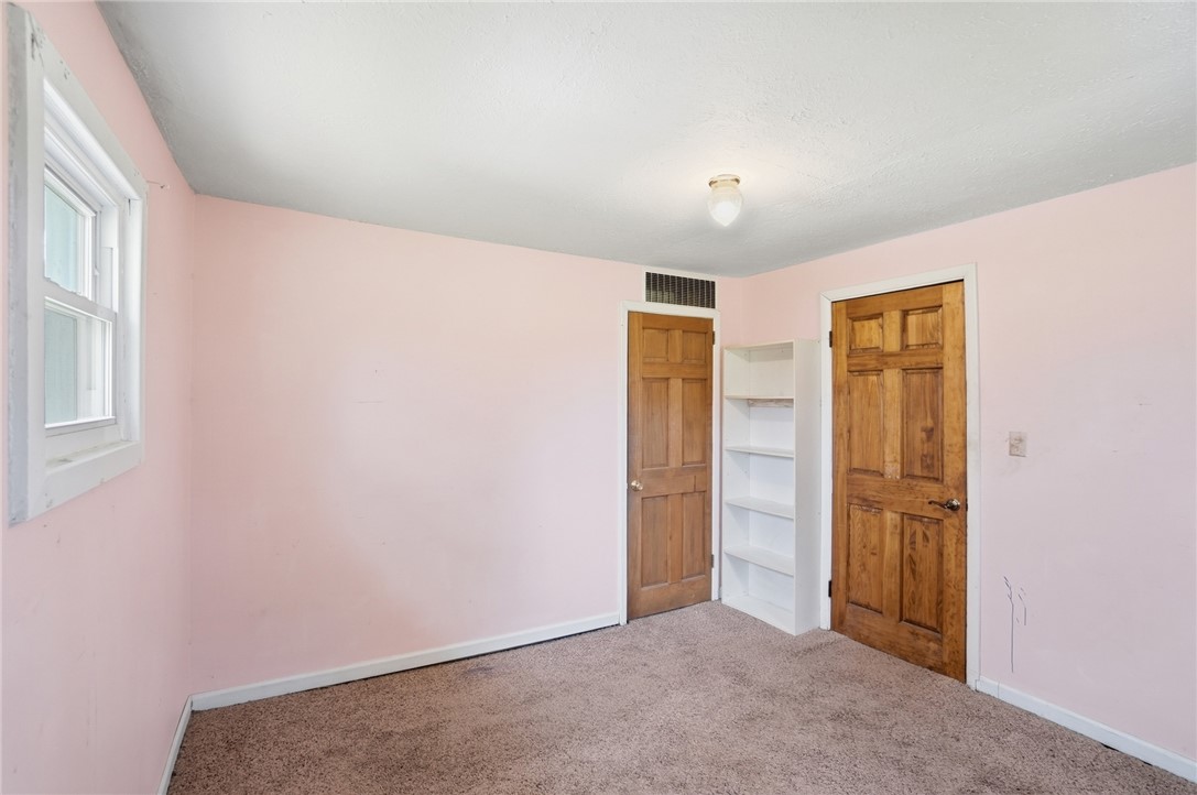 1166 West Sparrow Road Springfield, OH 45502 - Photo 32 of 40 This cozy bedroom features warm wooden doors, a bright window, and comfortable carpeted flooring.