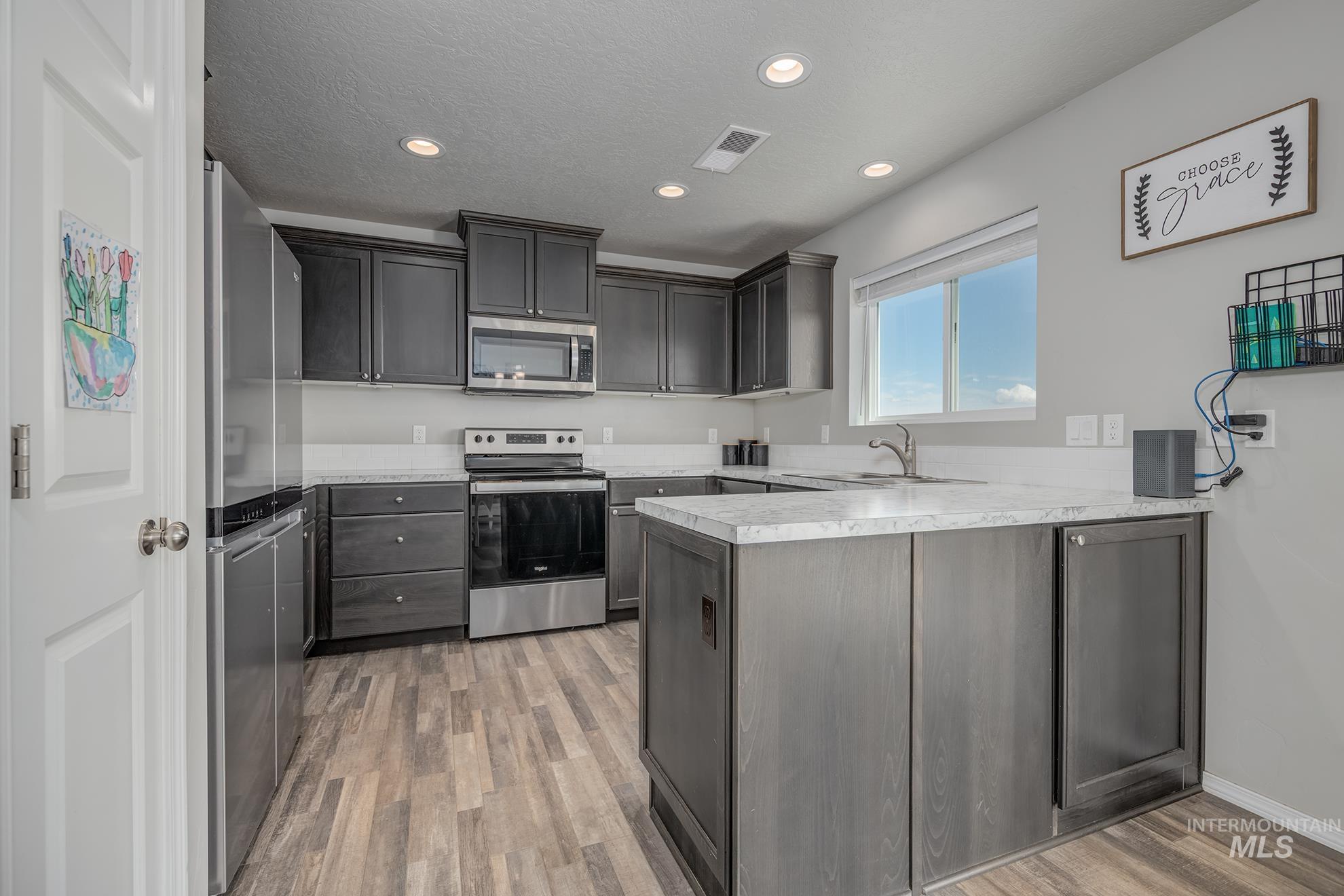 1049 Price Road Weiser, ID 83672 - Photo 8 of 47 Modern kitchen featuring dark wood-finish cabinetry, stainless steel appliances, light-toned countertops, and recessed lighting