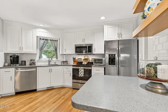 a kitchen with granite countertop a refrigerator a sink a stove top oven a cabinetry and kitchen island