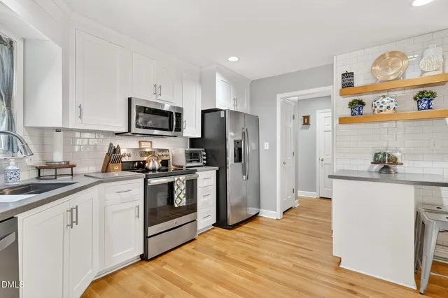 a kitchen with stainless steel appliances granite countertop a refrigerator a stove top oven a sink and dishwasher with wooden floor