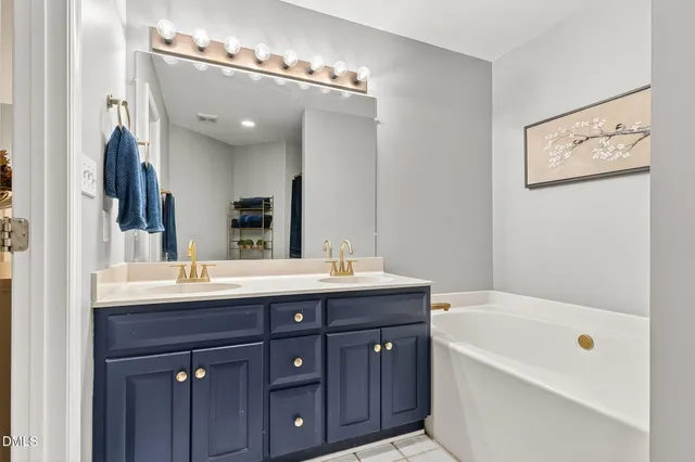 a bathroom with a tub a double vanity sink and mirror