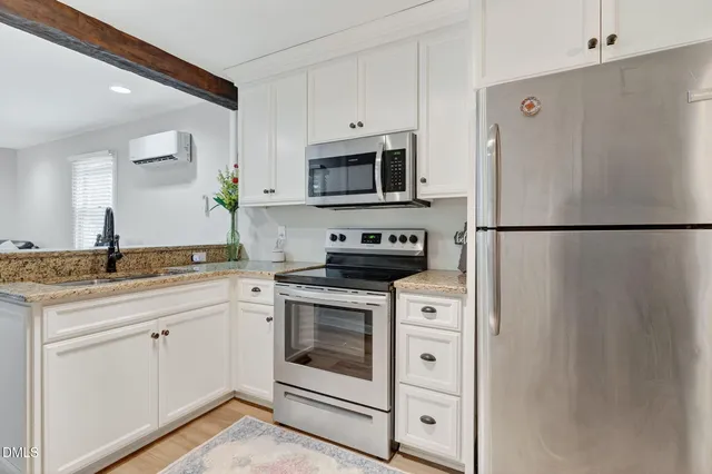 a white kitchen with stainless steel appliances granite countertop a refrigerator sink and stove