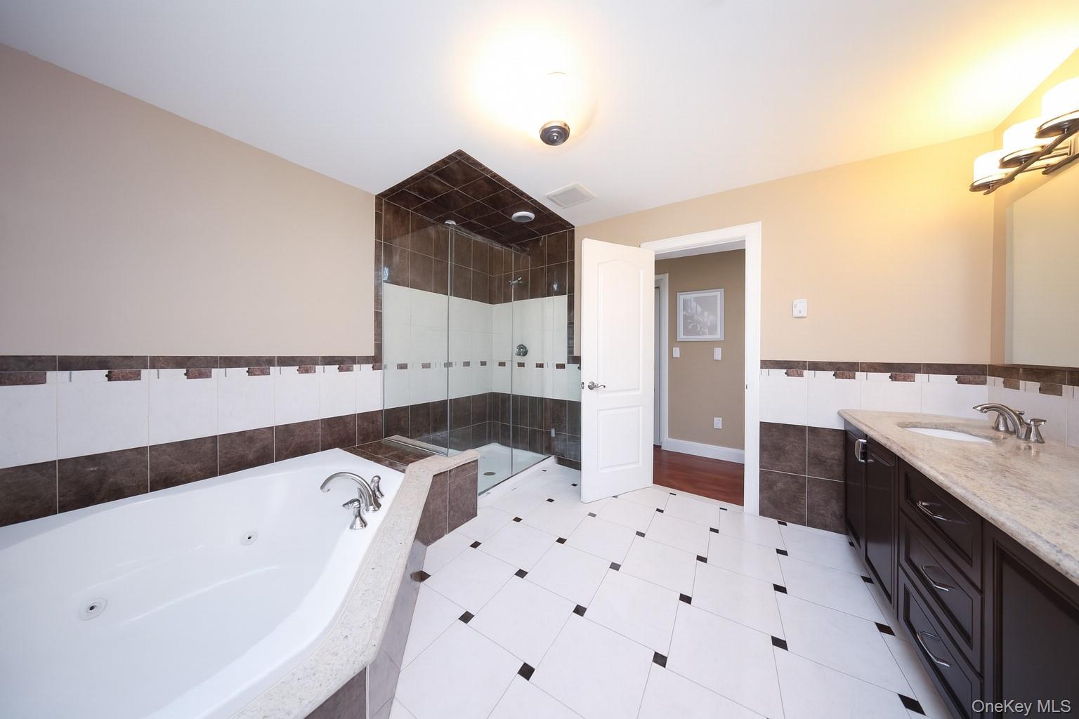 104 Highland Road Staten Island, NY 10308 - Photo 12 of 46 Bathroom featuring a tub with jets, vanity, tile walls, a stall shower, and wainscoting