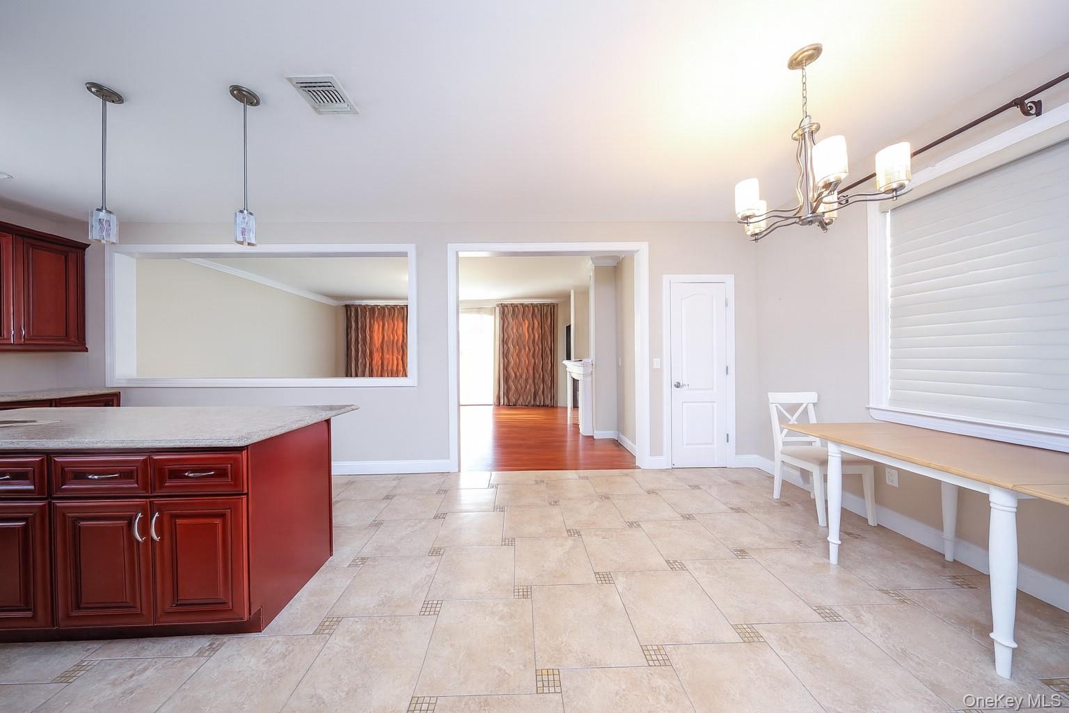 104 Highland Road Staten Island, NY 10308 - Photo 28 of 46 Kitchen with decorative light fixtures, a chandelier, dark brown cabinets, and light stone counters