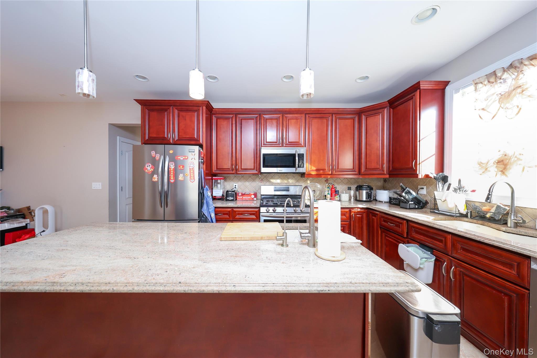 104 Highland Road Staten Island, NY 10308 - Photo 31 of 46 Kitchen featuring dark brown cabinets, an island with sink, stainless steel appliances, light stone counters, and recessed lighting