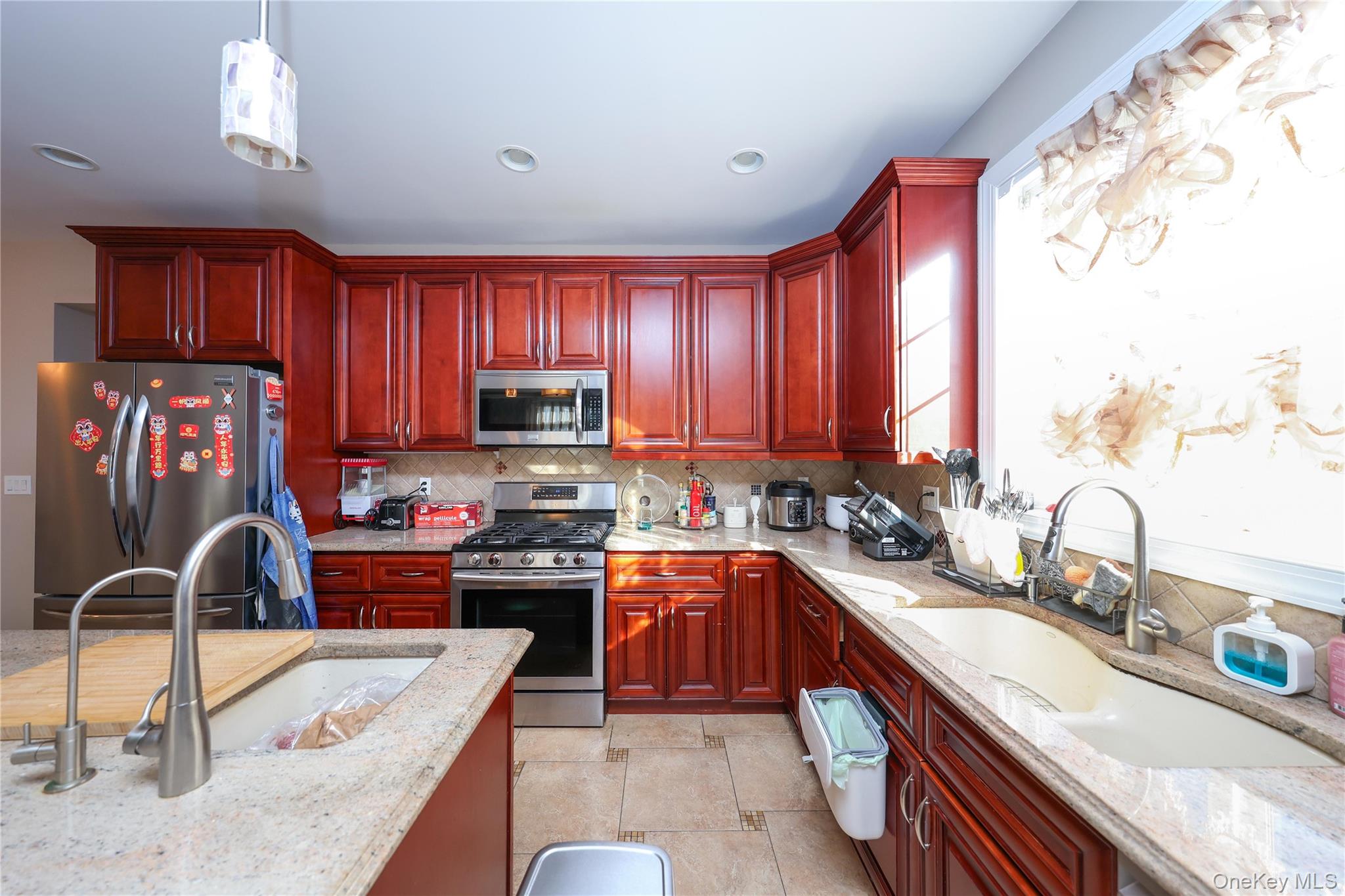 104 Highland Road Staten Island, NY 10308 - Photo 32 of 46 Kitchen with dark brown cabinets, appliances with stainless steel finishes, light stone countertops, and hanging light fixtures