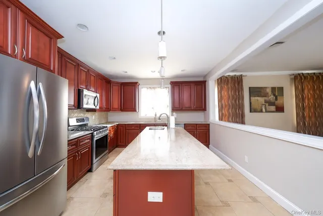 a kitchen with stainless steel appliances granite countertop a refrigerator a stove and a sink with wooden floor