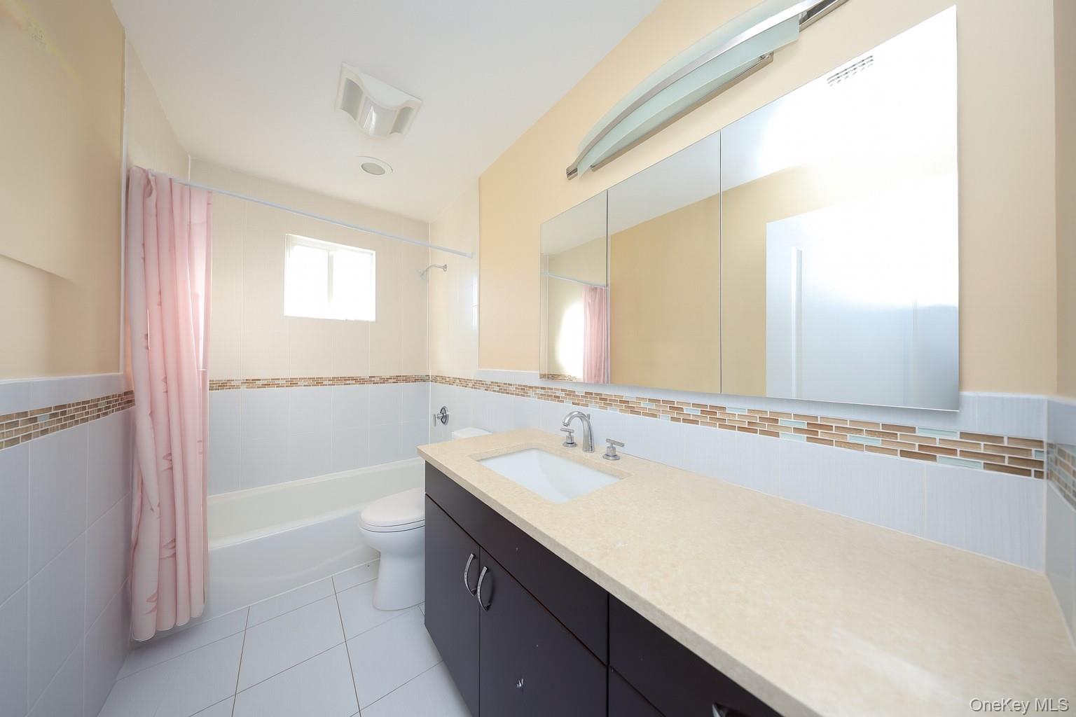 104 Highland Road Staten Island, NY 10308 - Photo 9 of 46 Full bathroom with tile walls, shower / bathtub combination with curtain, vanity, light tile patterned flooring, and a wainscoted wall