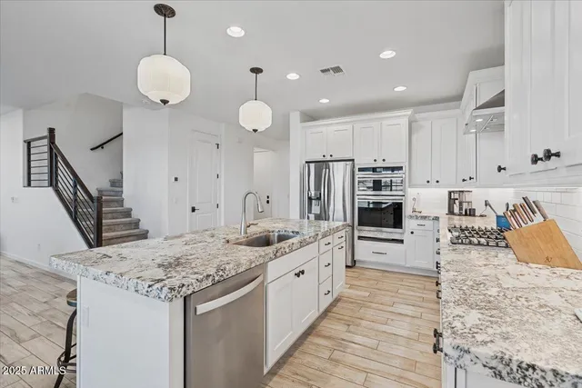 a large kitchen with stainless steel appliances granite countertop a stove and cabinets