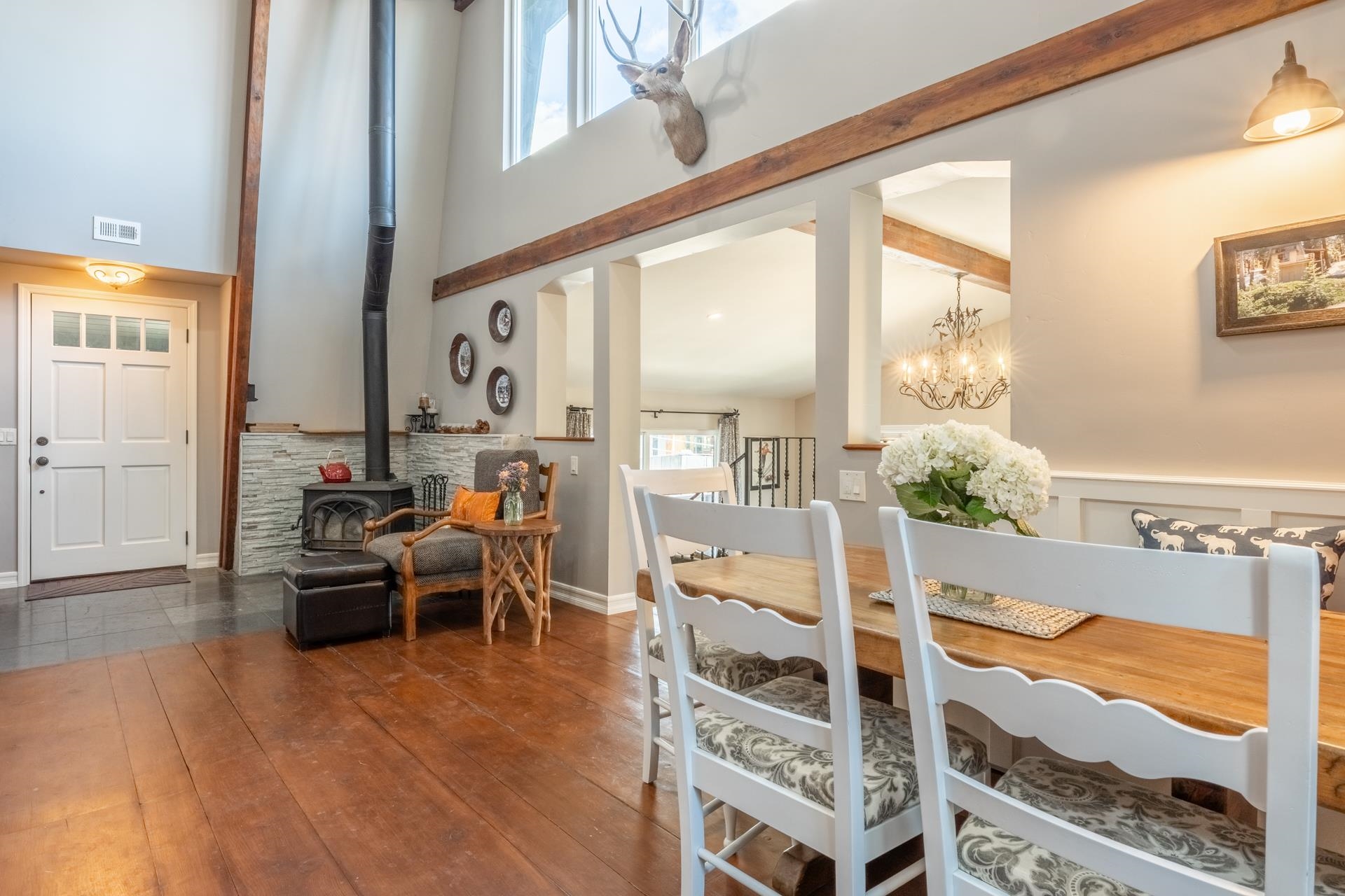 349 Davison Road Mammoth Lakes, CA 93546 - Photo 6 of 43 Dining room with a wood stove, a high ceiling, dark wood finished floors, beam ceiling, and a chandelier