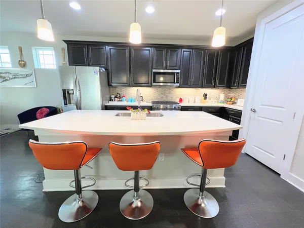 a kitchen with stainless steel appliances granite countertop a sink a stove a kitchen island a dining table and chairs