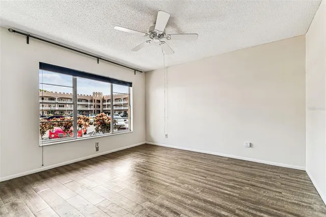 a view of empty room with wooden floor and fan