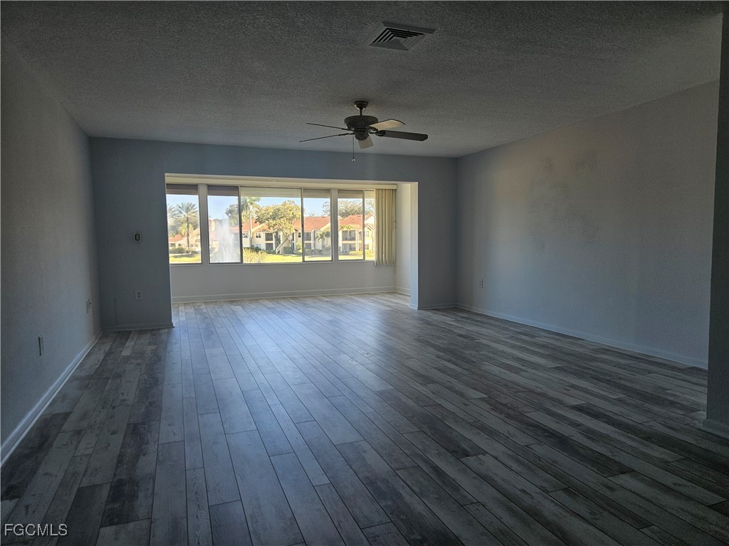 1830 Brantley Road, Unit F204 Fort Myers, FL 33907 - Photo 13 of 23 an empty room with wooden floor chandelier fan and windows