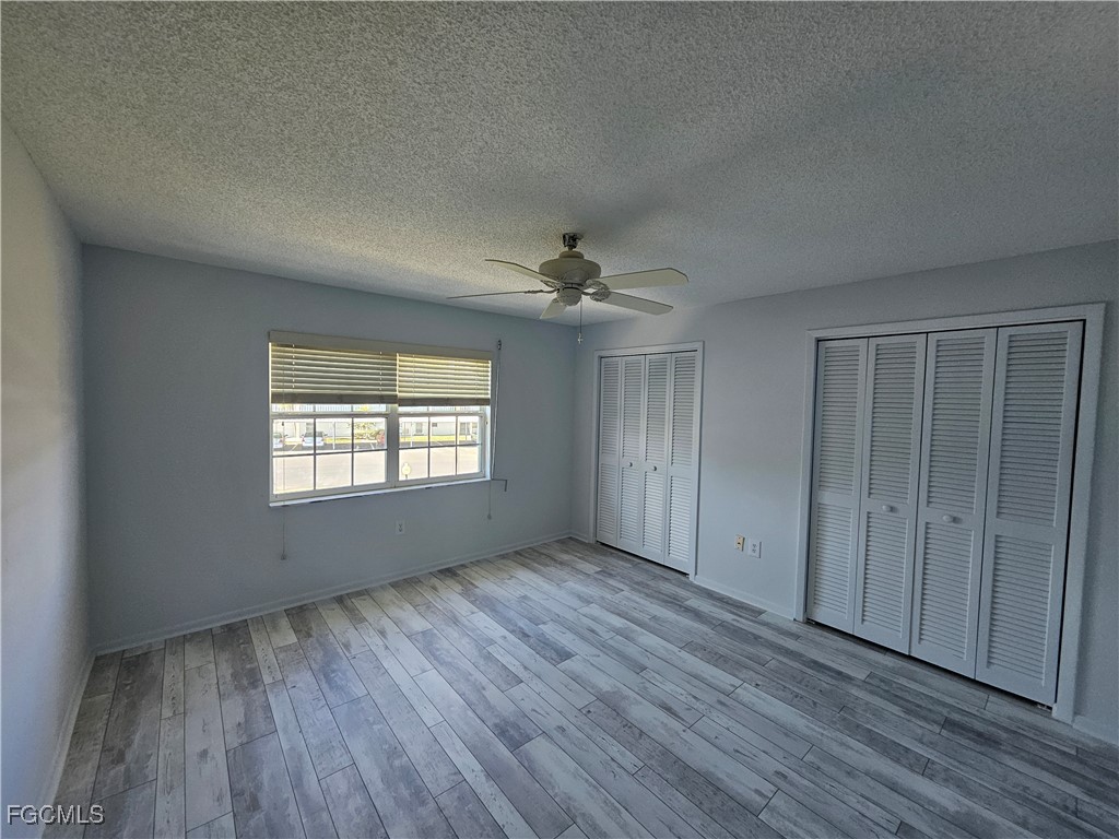 1830 Brantley Road, Unit F204 Fort Myers, FL 33907 - Photo 6 of 23 an empty room with wooden floor chandelier fan and windows