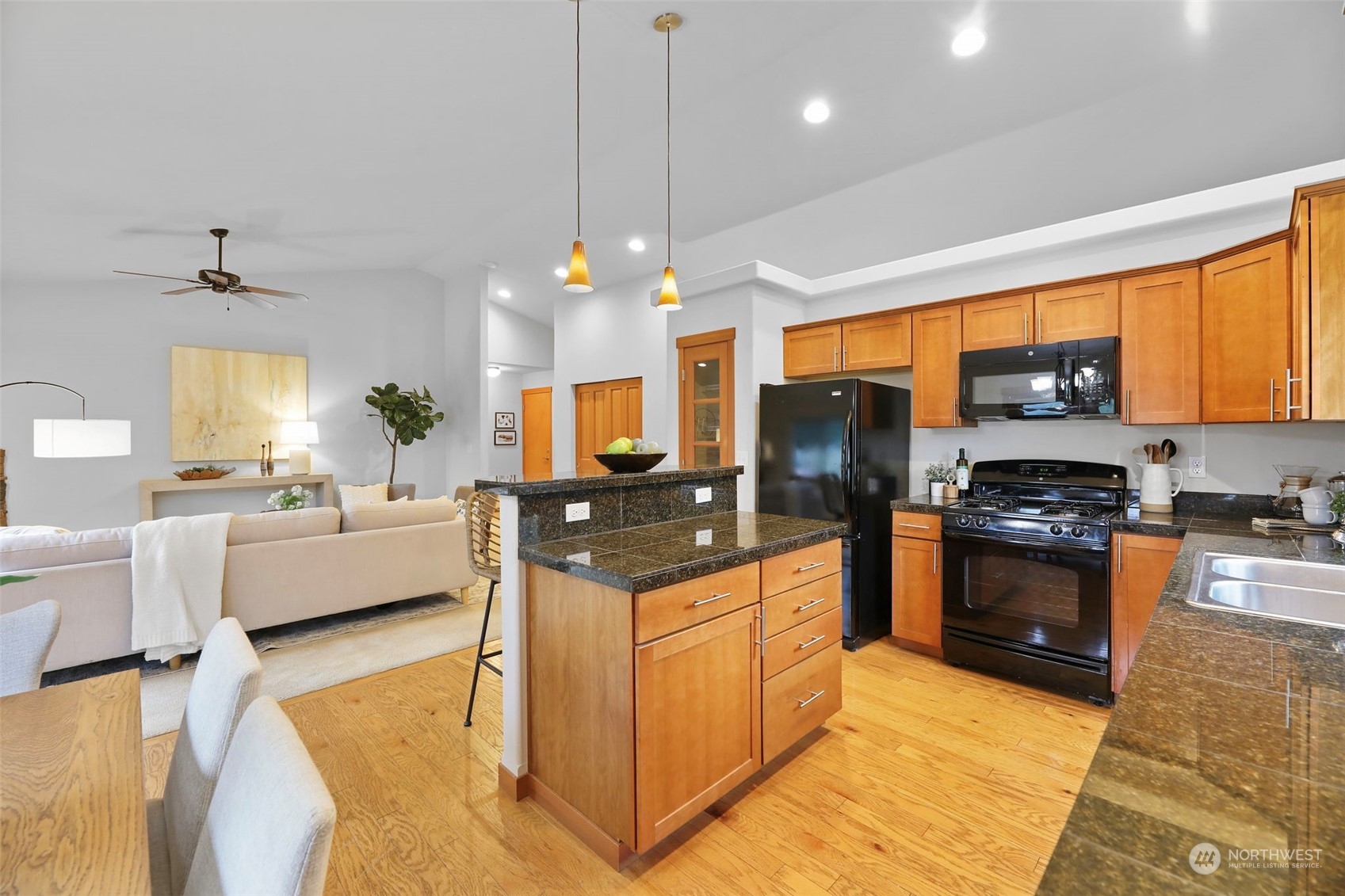 910 209th Street Southeast Bothell, WA 98021 - Photo 11 of 28 a kitchen with stainless steel appliances granite countertop a stove top oven a sink dishwasher a dining table and chairs with wooden floor