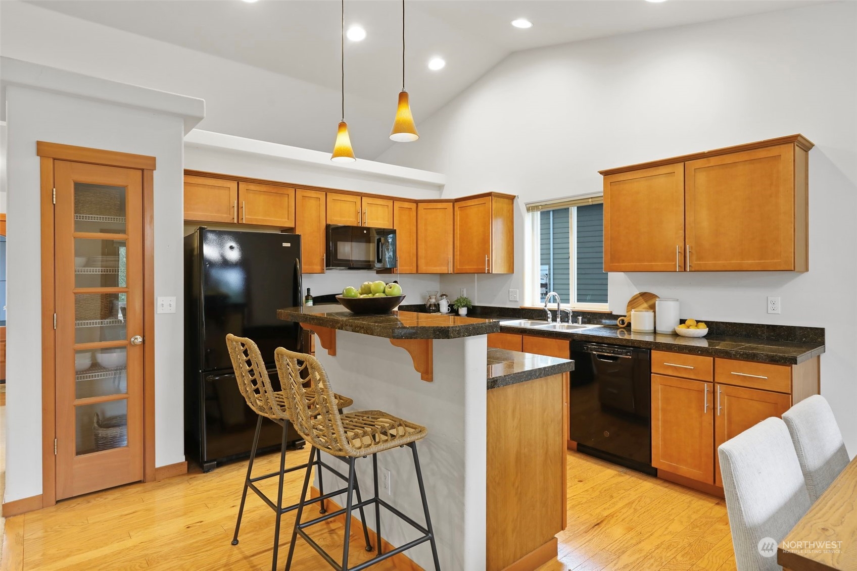 910 209th Street Southeast Bothell, WA 98021 - Photo 10 of 28 a kitchen with stainless steel appliances granite countertop a refrigerator a stove top oven and a dining table with wooden floor