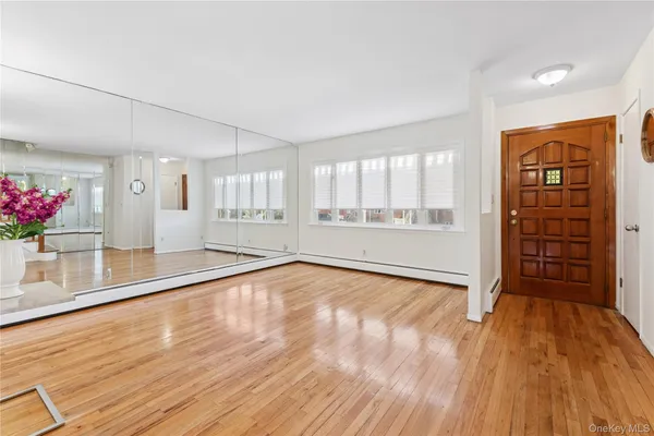 a view of an empty room with a window and wooden floor