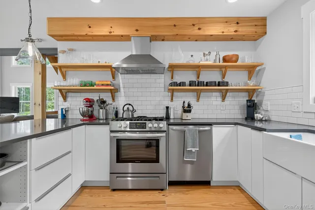 a kitchen with stainless steel appliances a stove and white cabinets