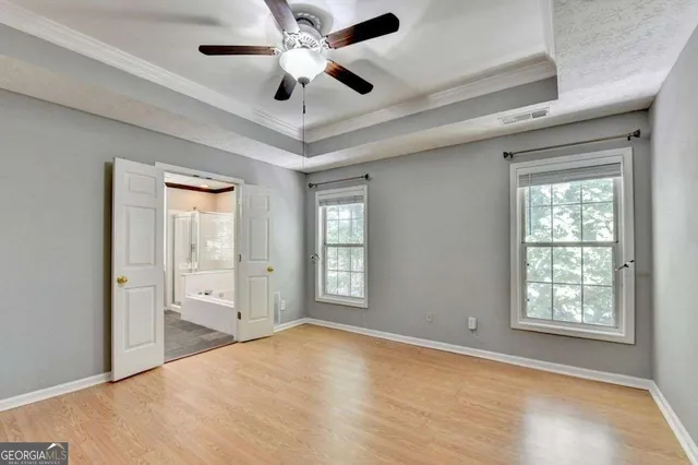 an empty room with windows and ceiling fan