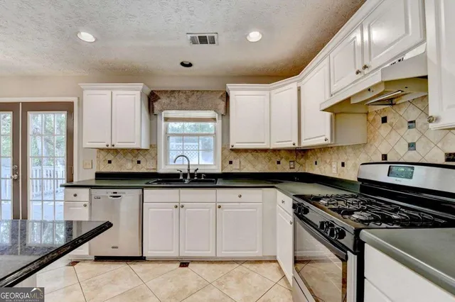 a kitchen with granite countertop a stove sink and cabinets