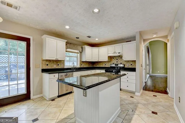 a kitchen with granite countertop a sink stainless steel appliances and cabinets