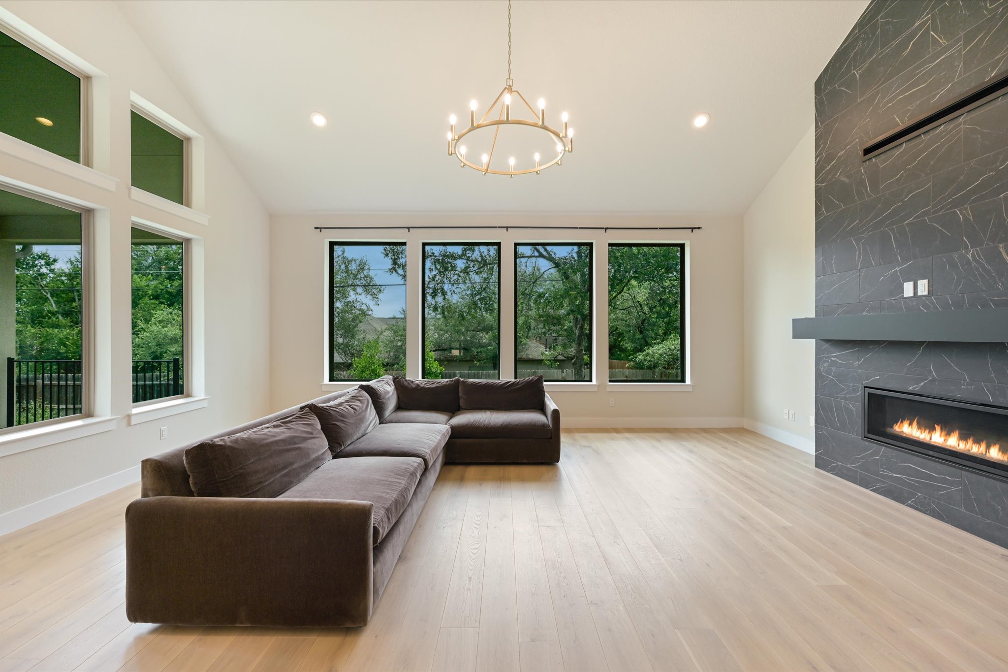 913 Presa Arriba Road Austin, TX 78733 - Photo 4 of 30 Natural light floods this living room with a striking floor-to-ceiling fireplace and wide plank flooring.