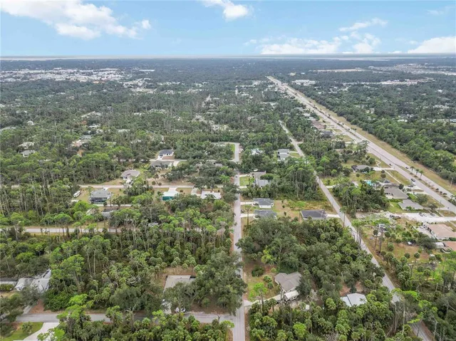 an aerial view of residential houses with outdoor space and trees