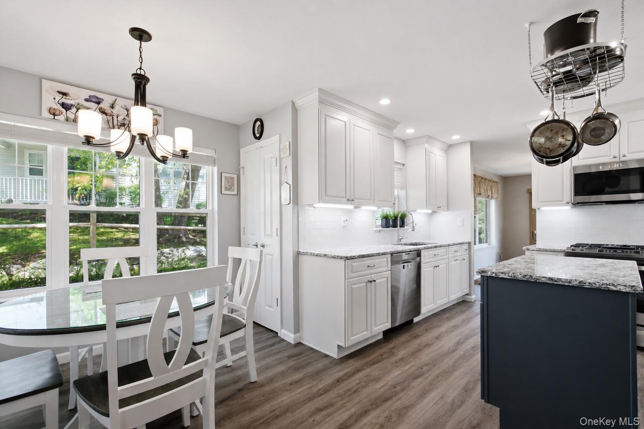 64 Roma Orchard Road Peekskill, NY 10566 - Photo 8 of 40 Open-concept kitchen featuring white shaker cabinetry, stainless steel appliances, granite countertops, and wood-finish flooring