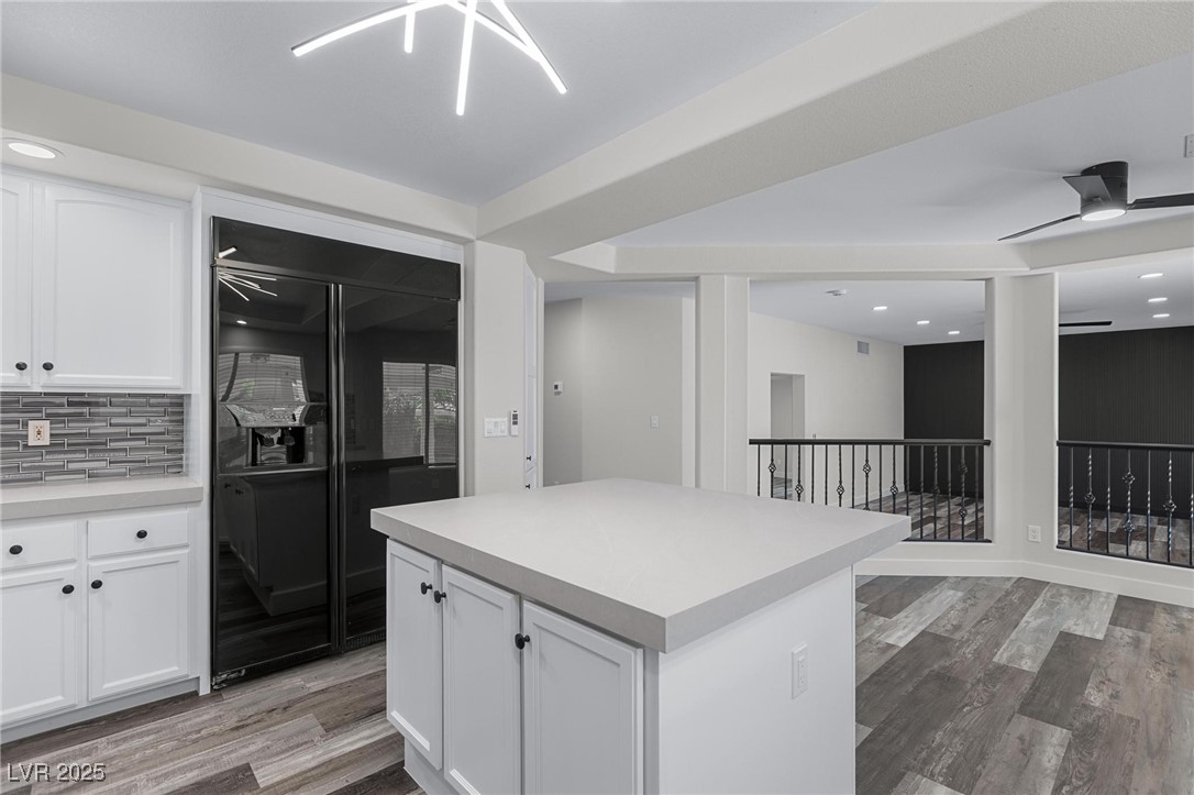 9591 Antelope Bend Court Las Vegas, NV 89148 - Photo 15 of 56 Kitchen with a tray ceiling, black appliances, glass insert cabinets, white cabinetry, and center island