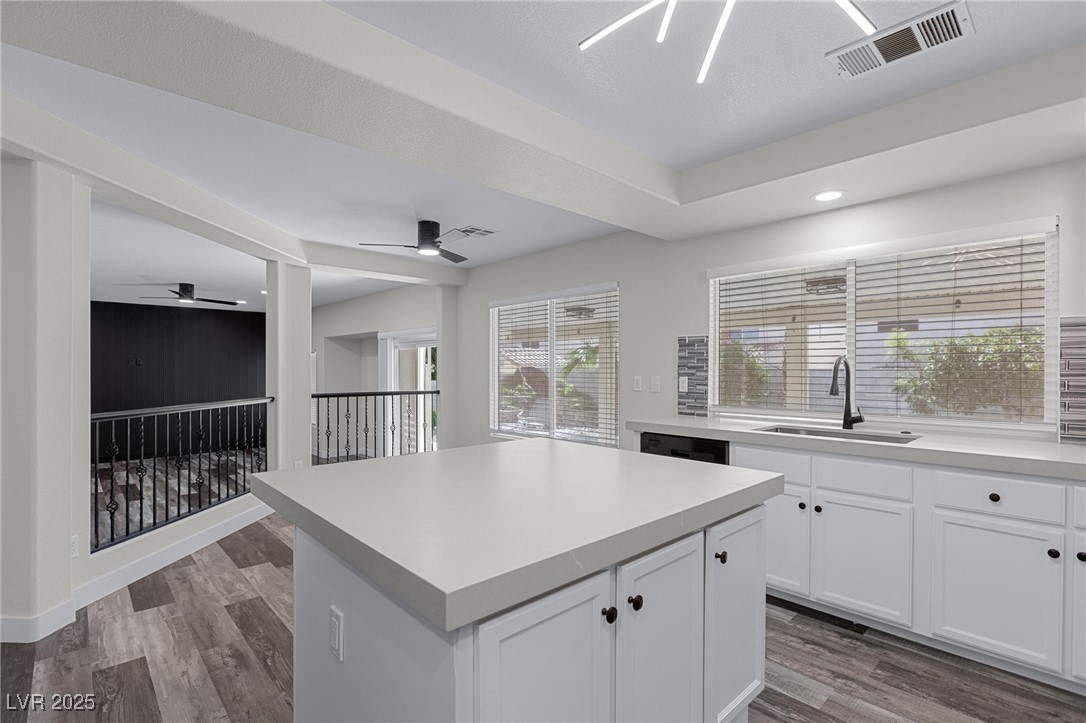 9591 Antelope Bend Court Las Vegas, NV 89148 - Photo 16 of 56 Kitchen with a tray ceiling, black appliances, glass insert cabinets, white cabinetry, and center island
